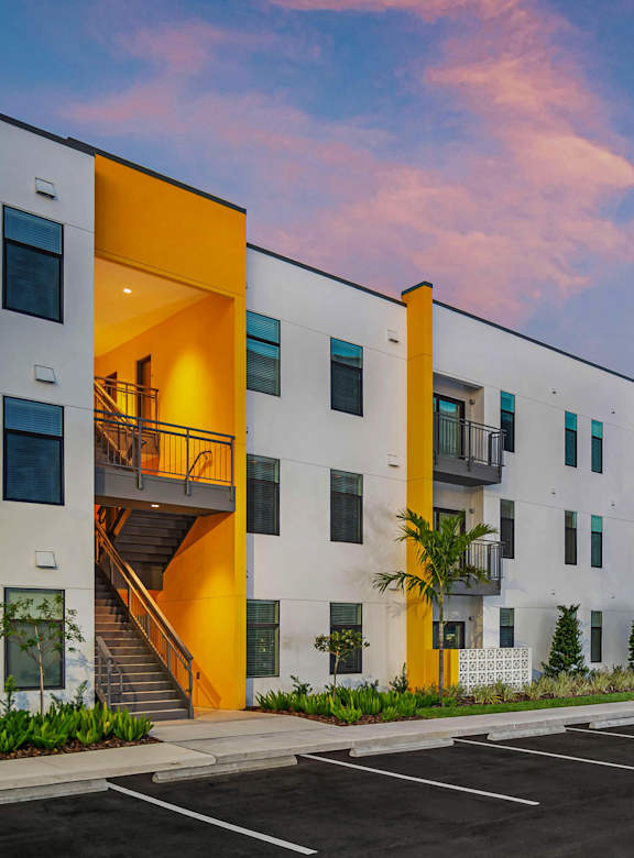 A modern apartment complex with a parking lot in front.