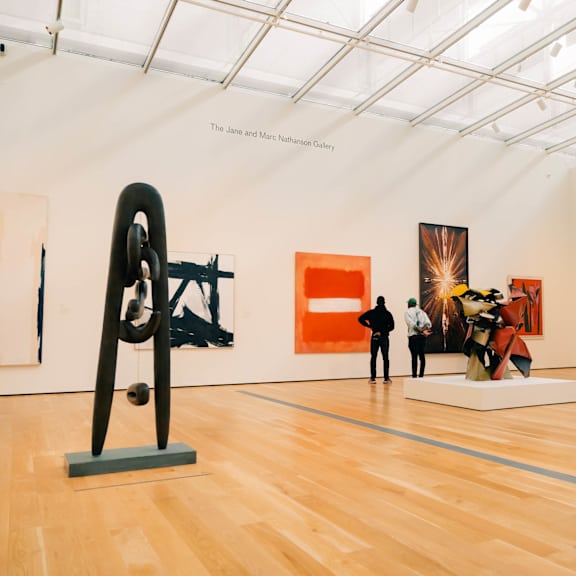 A gallery with a wooden floor and a sculpture on display.
