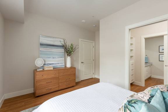 a bedroom with a bed and a dresser and a door to a bathroom