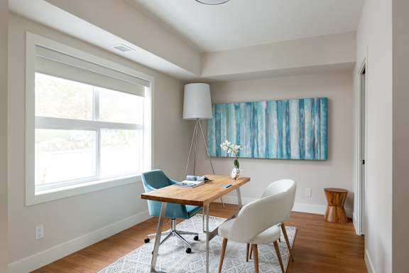 a home office with a desk and chairs and a large window