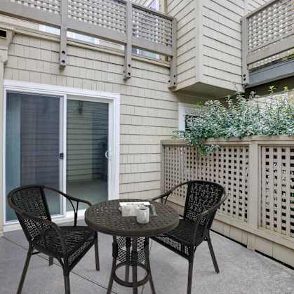 A patio with a table and chairs and a lattice fence.