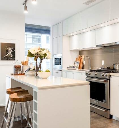 a white kitchen with stainless steel appliances and a counter top