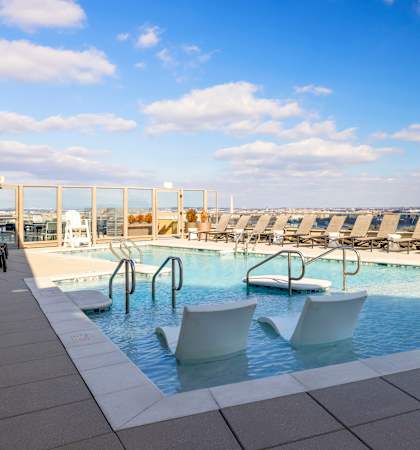 a large pool with chairs on top of a hotel roof at The Bartlett in Arlington, VA 22202