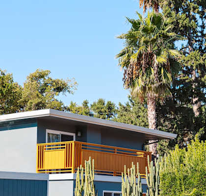 A house with a blue and grey exterior and a yellow railing.