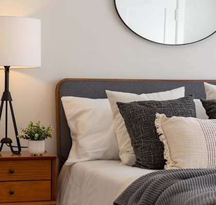 a bedroom with a bed with pillows and a mirror on the wall at Amity Senior, Amityville, NY 11701