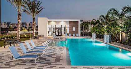 A pool surrounded by lounge chairs and palm trees.