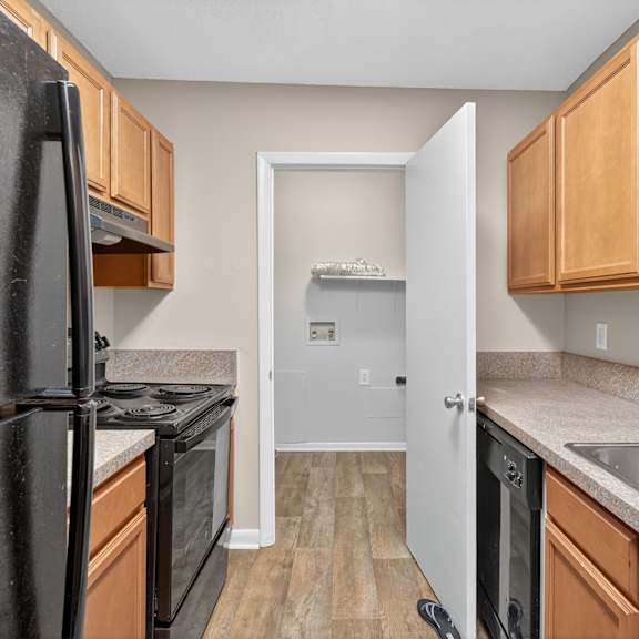 A kitchen with a black refrigerator and wooden cabinets. at Brackenbrook Apartments, North Charleston 29418