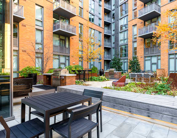 an outdoor patio with tables and chairs in front of an apartment building