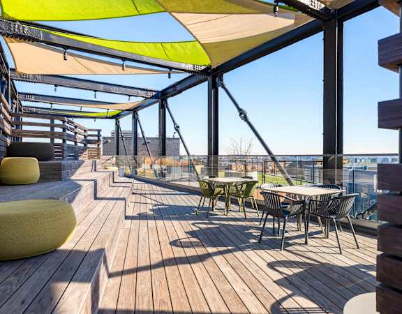 a roof deck with tables and chairs and a view of the city
