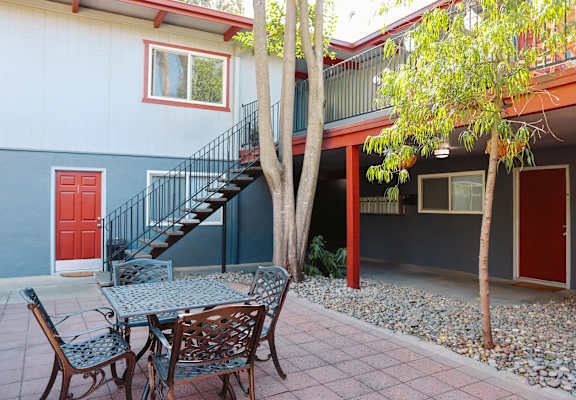 A patio with a table and chairs and a tree.