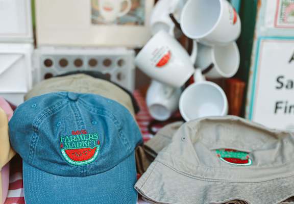 A blue cap with a watermelon logo is on a table with other caps.