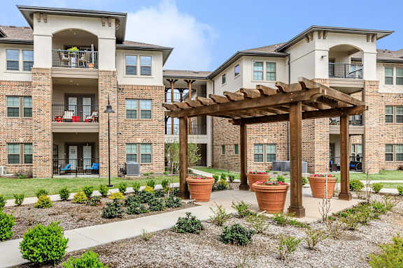 an outdoor area with potted plants in front of an apartment building at Mariposa at Westchester, TX 75052