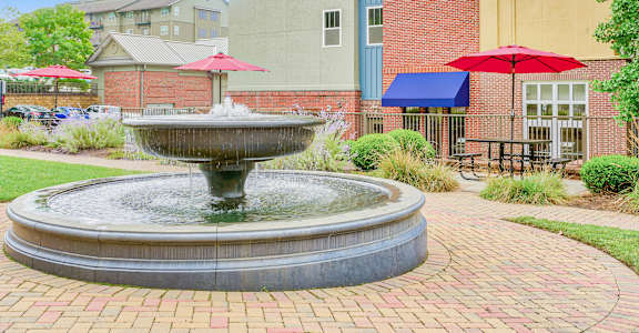 A fountain in the middle of a brick walkway. at The Lofts at Reynolds Village Apartments, Asheville