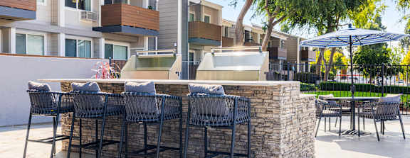 A patio with a bar and chairs is surrounded by apartment buildings.