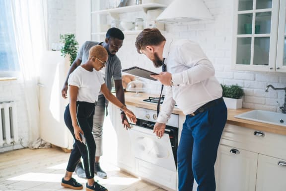 a group of people standing around a stove in a kitchen