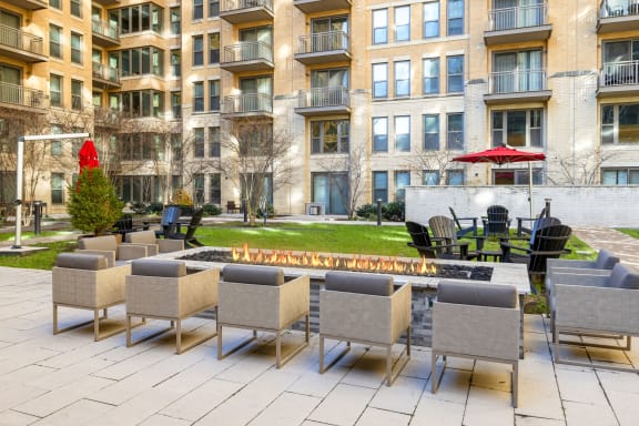 a patio with chairs and a fire pit in front of an apartment building at The Bartlett in Arlington, VA 22202