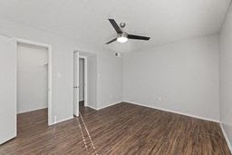 A room with a ceiling fan and wood flooring.