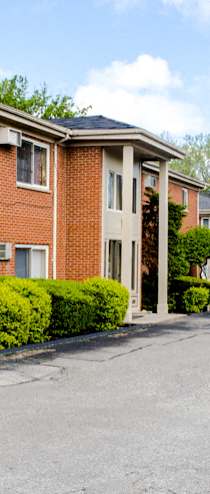 A red brick building with a sign that says "Hillcrest Manor Apartments" in front of it.