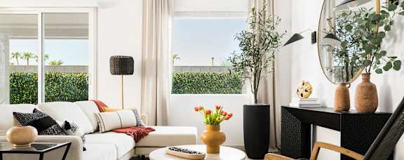A living room with a white sofa, a black table, and a large window with a view of the outside.