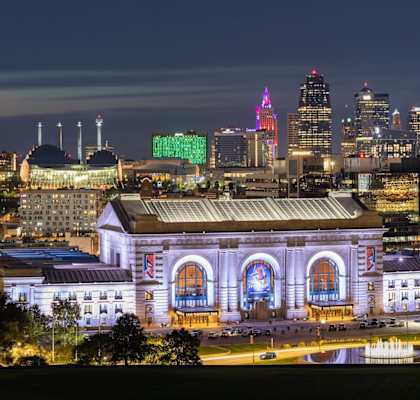 A cityscape at night with a prominent building in the foreground.