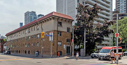 A red building with a red roof sits on a street corner. at 608 Church Apartments, Toronto, ON, M4Y 2E7