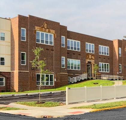 a large brick building with a white fence in front of it  at Hendricks Pointe Apts, Shelbyville, IN