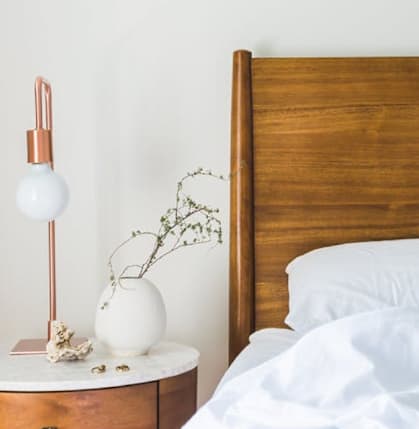 Model Bedroom with Wood Bed Frame and White Bedding Next to Wood Nightstand