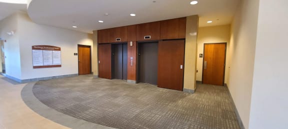 a view of three elevators in a large room with a rug