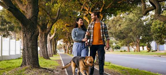 A man and woman walking a dog at Ophelia on Queen Apartments, Ontario
