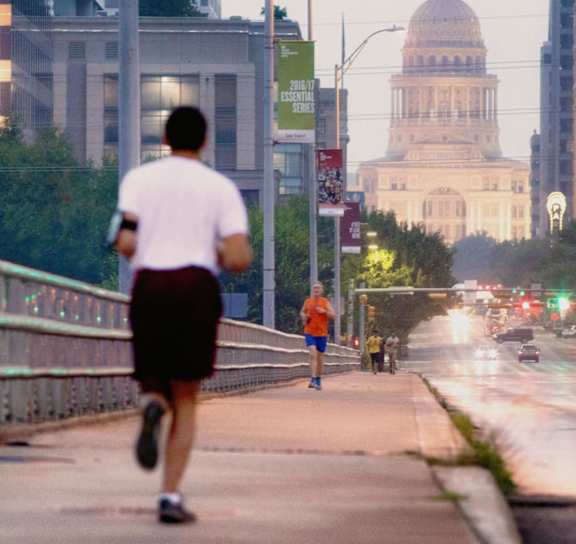 A man running on a bridge in a city at Arise Riverside Apartments, Austin, TX, 78741