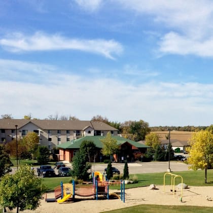 Hutchinson, MN Echo Manor |a park with a playground and apartment buildings in the background
