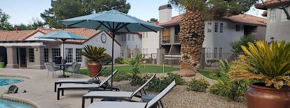 a patio with chairs and umbrellas next to a swimming pool