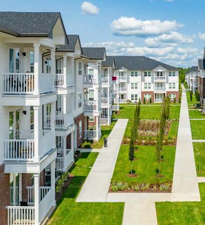 A row of modern apartment buildings with green lawns in front.
