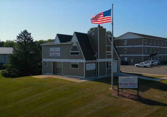 A building with a sign that says "Suite Liv'n Rental Office" is in front of a flag.