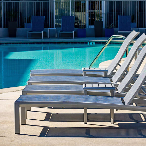 Chaise Lounge Chairs Sitting in Front of a Sparkling Blue Swimming Pool in the Sunshine at The Crossings at Redlands, in Redlands, CA