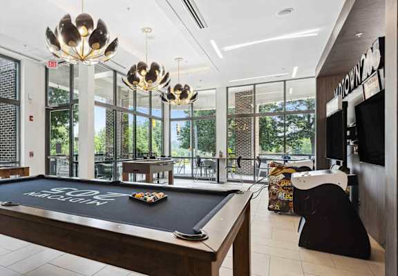 A pool table in a room with a view of trees outside the window.