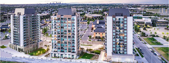 A cityscape with modern buildings and a parking lot in the foreground.