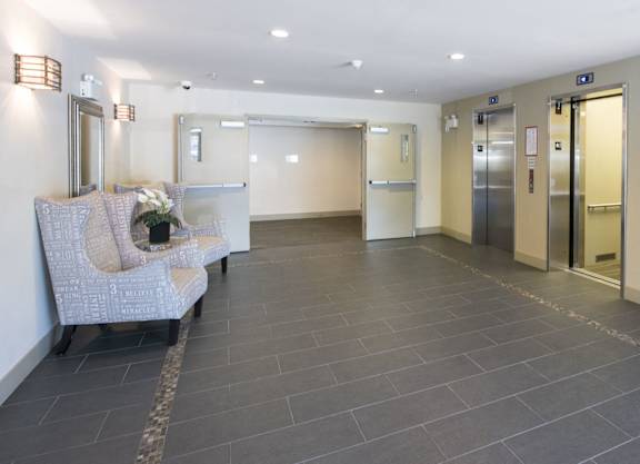 a hallway with a couch and a chair in a building with elevators