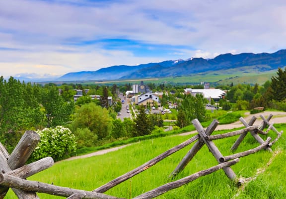 a rustic wooden fence on a green hillside with a village in the background at Copper Pines, Bozeman