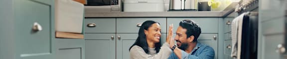 Couple high fiving in front of cabinets