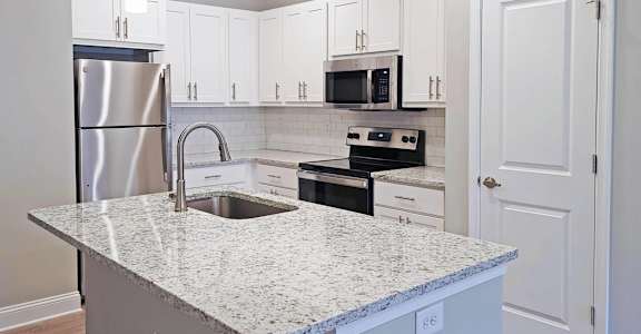 A kitchen with a granite countertop and white cabinets.