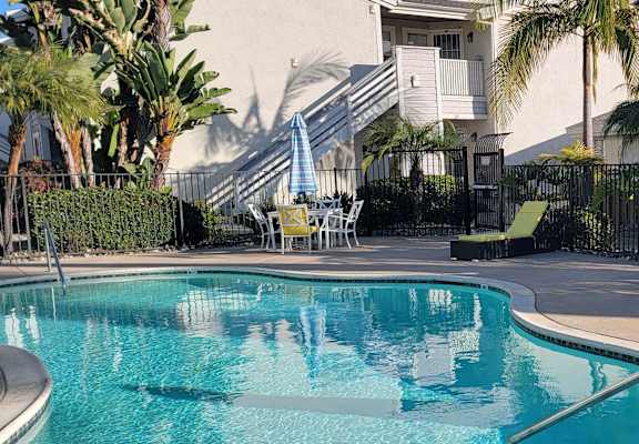 A pool with a blue umbrella and a white chair.