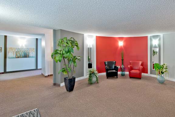 A living room with a red couch and a potted plant.
