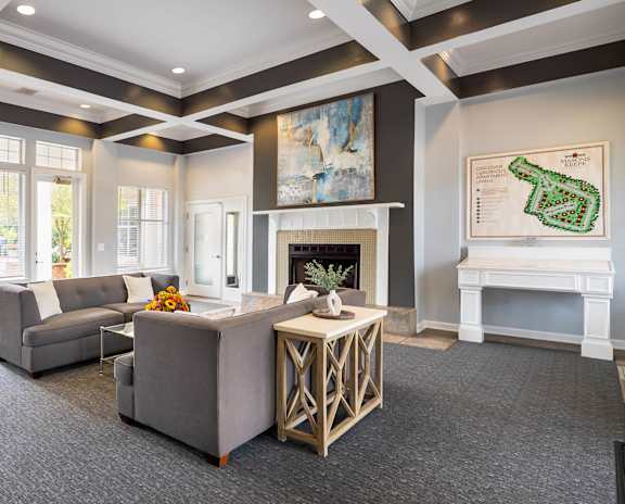 Clubhouse lounge with a grey couch and a white fireplace.