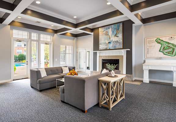 Clubhouse lounge with a grey couch and a white fireplace.
