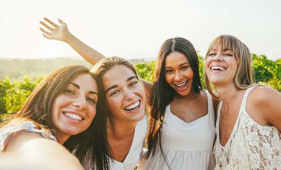 Four women taking a selfie in a field.