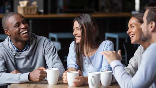 Four people are sitting around a table, laughing and enjoying each other's company.