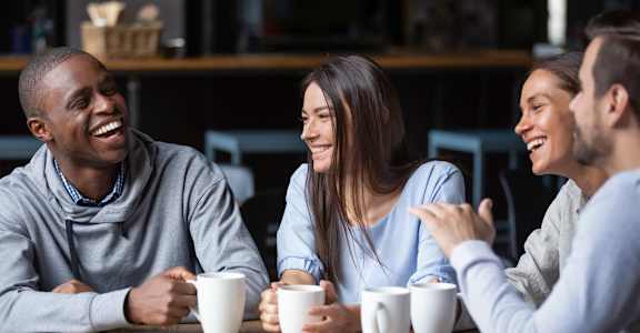 Four people are sitting around a table, laughing and enjoying each other's company.