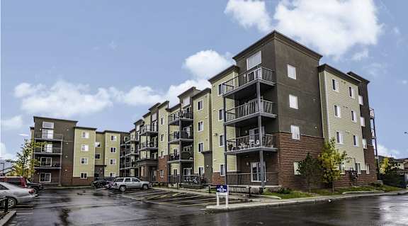 A large apartment building with a parking lot in front.