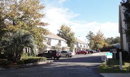 a street with houses on either side and cars parked on the side of the road